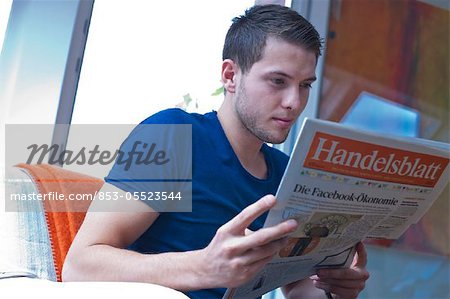 Young man reading newspaper