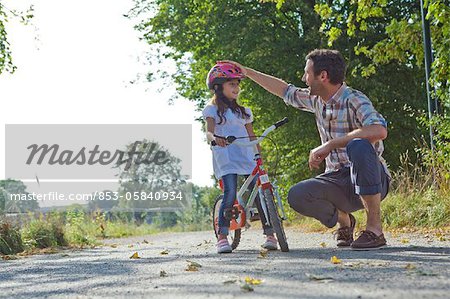 Father and daughter with helmet on bike outdoors