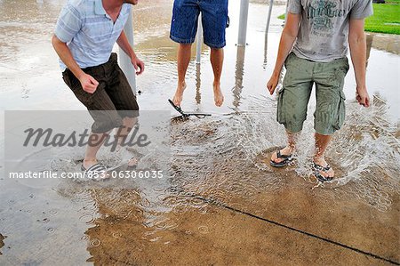 Three young men jumping in puddles