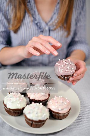 Woman putting garnish on muffins on plate