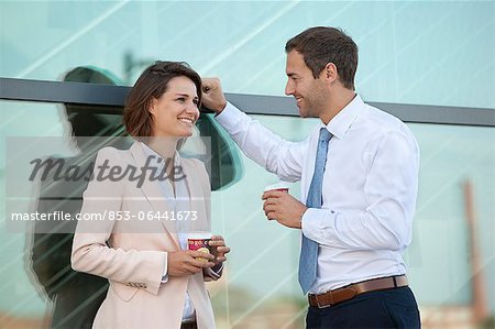 Businessman and businesswoman with coffee to go talking