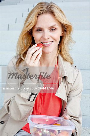 Blond woman having a snack on stairs