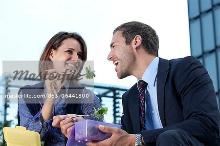 Businessman and businesswoman eating outdoors