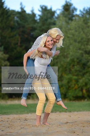 Cheerful woman holding on to boyfriends head while having piggyback ride  stock photo