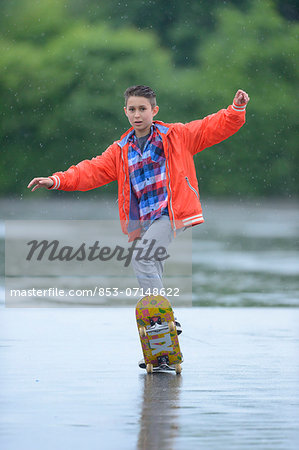 Boy with skateboard on a rainy day