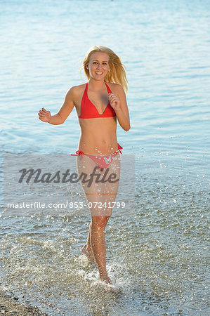 Young blond woman running in a lake, Styria, Austria
