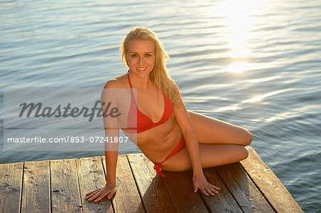 Young blond woman in bikini on a jetty at a lake, Styria, Austria