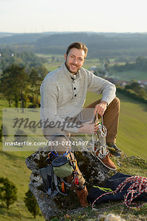 Man sitting on a rock with climbing equipment