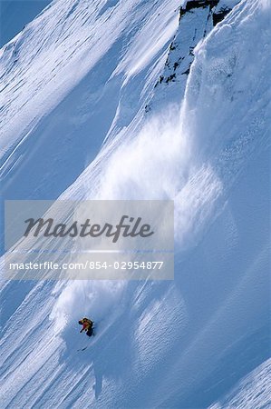 Extreme skier skis down steep snow covered mountain Chugach Mountains Valdez Southcentral Alaska Winter
