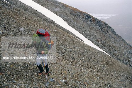 Female backpacker approaches the top of a pass at Wrangell-St.Elias National Park in Southcentral Alaska.