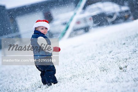 Portrait of girl infant wearing a Santa hat and walking in snow during Winter in Southcentral Alaska