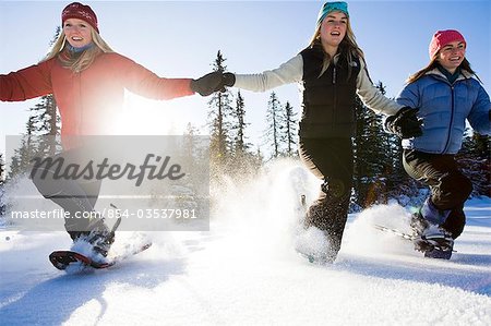 Three young women on snowshoes enjoy the outdoors near Homer, Alaska during winter.