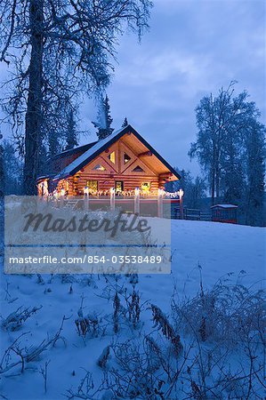 Log Cabin In The Woods Decorated With Christmas Lights At Twilight