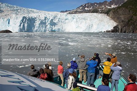Tourists view glacier from the bow of a Kenai Fjords tour of Resurrection Bay, Seward, Alaska