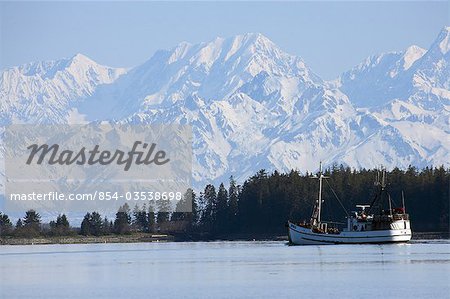 Scenic view of the St. Elias Range with a fishing schooner in the foreground near Yakutat, Alaska