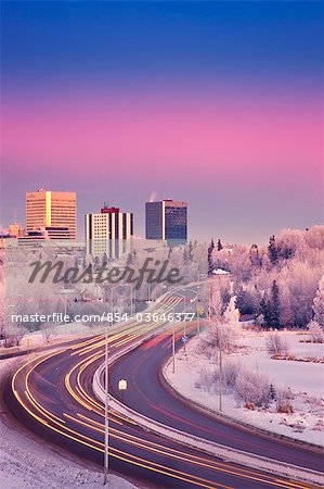 Sunset view of traffic on Minnesota Blvd. with downtown Anchorage in the background, Southcentral Alaska, Winter/n