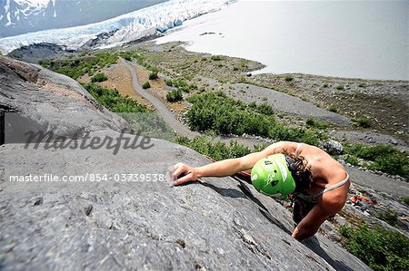 Woman rock climbing with Spencer Glacier in the background, Chugach National Forest, Kenai Peninsula, Southcentral Alaska, Summer