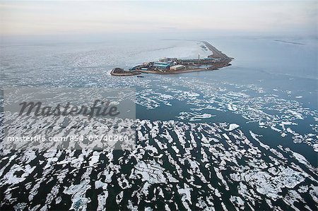 Aerial view of an oil well drilling platform on a man-made island and surrounded by broken sea ice, Prudhoe Bay, Beaufort Sea near Deadhorse, Arctic Alaska, Summer