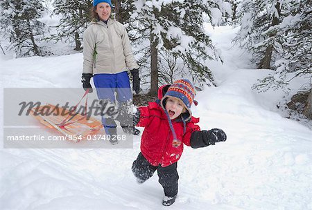 Preschool age boy throwing a snow ball while his mother watches on, Chugach State Park, Southcentral Alaska, Winter