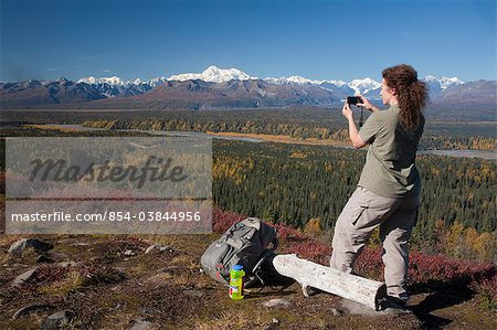 Female hiker photographs the view of Mt. Mckinley and Alaska Range from Kesugi Ridge Trail near Little Coal Creek trailhead, Denali State Park, Southcentral Alaska, Autumn