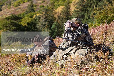 Two male moose hunters scope and glass for game in the Bird Creek drainage area, Chugach Mountains, Chugach National Forest, Southcentral Alaska, Autumn
