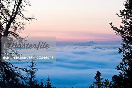 Scenic view of a low layer of fog over Anchorage with Mt. Redout visible above the fog  in the background, Southcentral Alaska, Winter