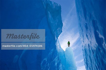 An ice climber surveys a wide crevasse from within Mendenhall Glacier, Juneau, Southeast Alaska, Winter