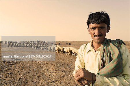 Portrait of a shepherd with a flock of sheep behind him, Jaisalmer, Rajasthan, India
