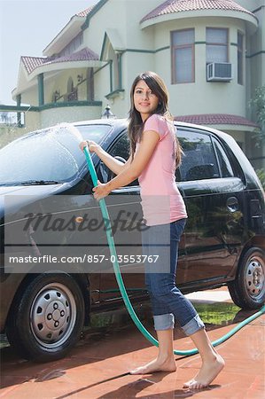 Woman washing a car and smiling, New Delhi, India