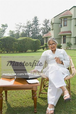 Woman working on a laptop in a lawn, New Delhi, India