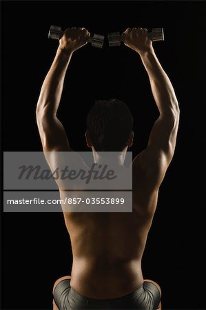 Rear view of a man exercising with dumbbells