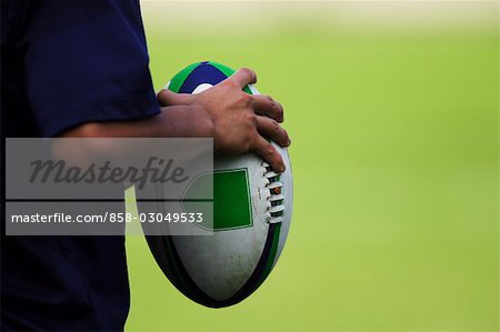 Close up of rugby ball held by player