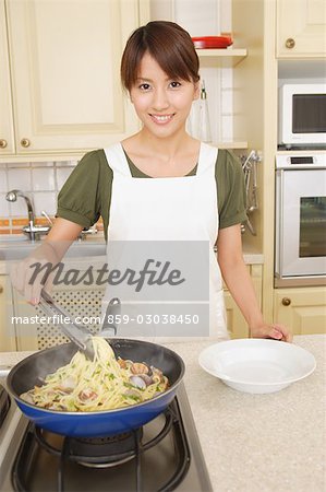 Front view of a woman frying noodles