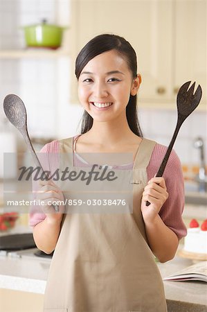 Close-up of a young smiling woman holding serving utensils
