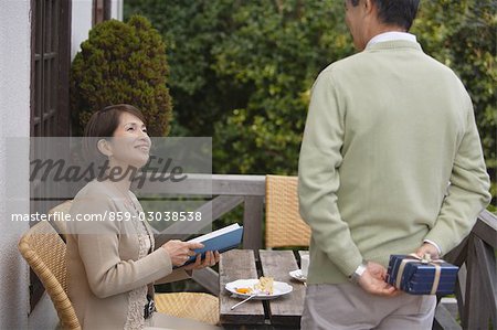Rear view of a man holding gift while woman looking at him