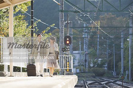 Front view of couple walking on railway platform