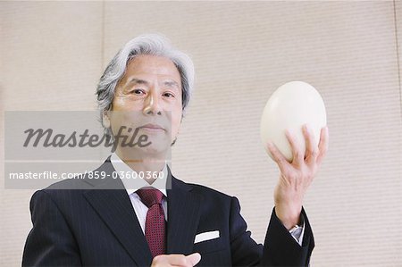 Executive Businessman Holding Egg Of Ostrich