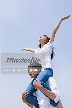 Woman Sitting on Husband's Shoulders with Arms Outstretched
