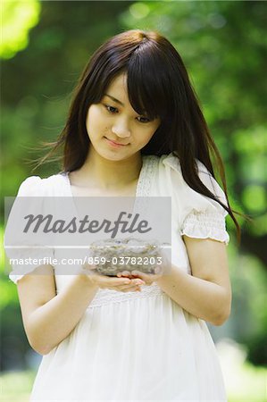 Young Woman Standing  Holding Nest in Forest