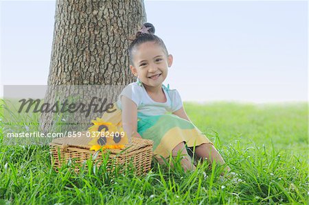 Girl Sitting with Flowers and Basket in Park