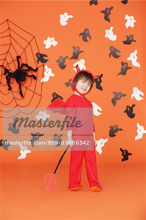 Boy Dressed Up As Devil against Orange Background