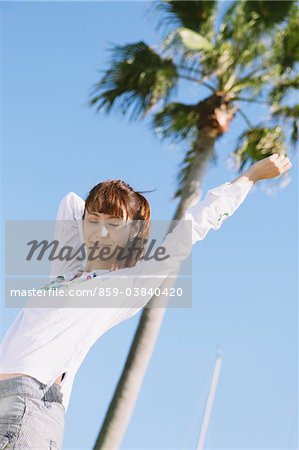 Young Woman Near A Palm Tree Arm Stretched