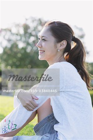 Pretty Young Woman Hugging Knees In Park