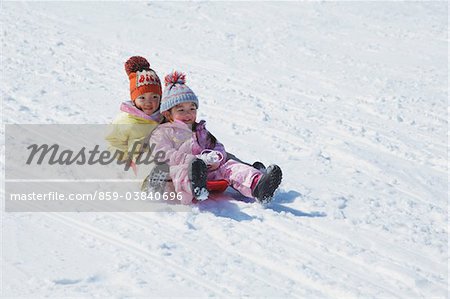 Small Sisters Sledging In Snow