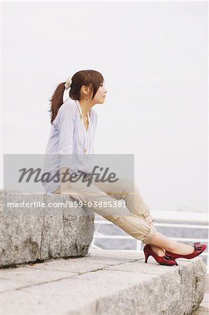 Pretty Young Women Sitting On Rock