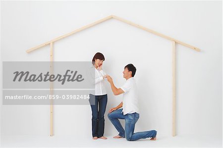Man Proposing Women In Front Of Hut Shape Made From Wood