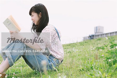 Japanese girl reading on a book on the grass