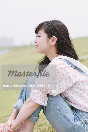 Japanese girl sitting on the grass looking away