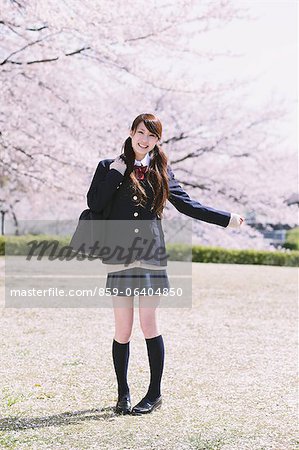 Japanese schoolgirl in her uniform with cherry blossoms in the background
