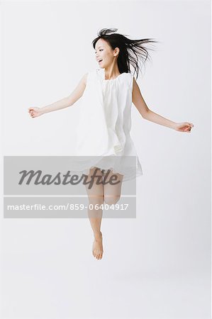 Asian woman in a white dress jumping